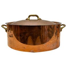 a large copper pot with handles on the top and bottom, sitting in front of a white background