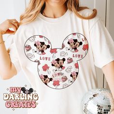 a woman wearing a mickey mouse t - shirt holding a disco ball in front of her face