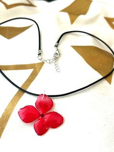 a red flower on a black cord necklace