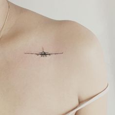 a small airplane tattoo on the back of a woman's left upper arm and shoulder