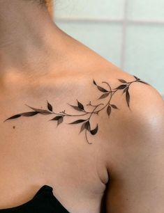 a woman with a tattoo on her shoulder that has leaves growing out of the back