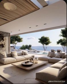 a living room with couches and tables in front of a large window overlooking the ocean