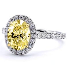 an oval yellow diamond surrounded by white diamonds in a halo setting with two rows of round brilliant cut diamonds surrounding the band