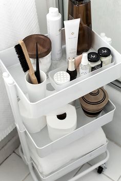 an organized bathroom shelf with toiletries and personal care items on the bottom shelf, in front of a mirror