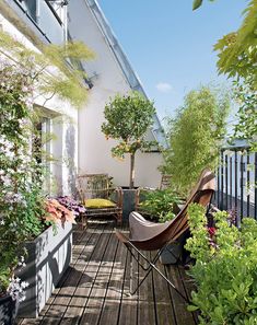 an outdoor deck with potted plants and chairs