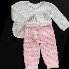 a pink and white crocheted outfit with pom - poms on it