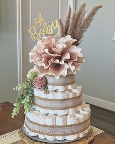 a three tiered cake decorated with flowers and diapers