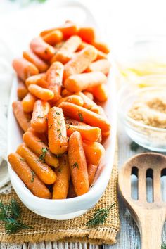 there is a bowl full of carrots and other food items on the table with utensils