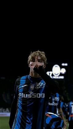 a man standing on top of a soccer field holding his hand up to his face