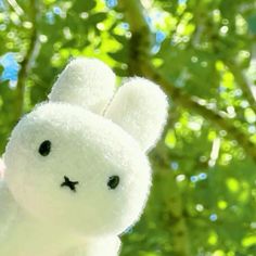 a small white stuffed animal sitting on top of a tree