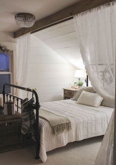 a white bed sitting under a window in a bedroom