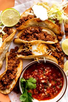 tacos and salsa on a plate with lime wedges