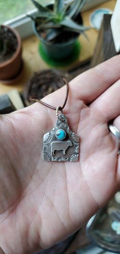 "Let me make an adorable cow tag charm turquoise pendant for you! These are so fun, and would be beautiful gifts for any cowgirl friend or bridesmaid. Convo me for different stones or personalized stamping requests for this pendant. A name or date can be stamped on the back for an additional charge. Sterling silver measuring 7/8\" wide by 1 1/8\" tall. Choices for cords and chains are in the drop down menu. Thanks for looking! Please note each item is handmade and will be slightly different from Turquoise Nickel-free Charm Necklace As Gift, Turquoise Dangle Charm Necklaces For Gifts, Turquoise Dangle Charm Necklaces As Gift, Nickel Free Turquoise Charm Necklace For Gift, Nickel-free Turquoise Charm Necklace Gift, Stamped Sterling Silver Turquoise Necklace For Gift, Stamped Sterling Silver Turquoise Necklace As Gift, Blue Stamped Jewelry For Gifts, Blue Stamped Jewelry For Gift