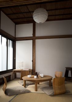 an empty room with two chairs and a round table in the middle, next to large windows