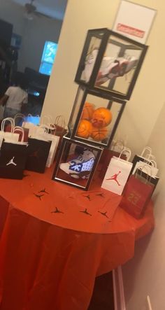 an orange table topped with shopping bags and small boxes filled with basketballs on top of it