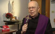 an older man in a priest's robes holding a cross