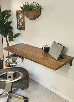 a desk with a laptop on it next to a chair and potted plant in the corner