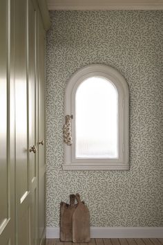 an arched window in the corner of a room with wooden flooring and wallpaper