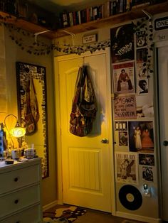 a yellow door in a small room with posters on the wall and pictures hanging above it