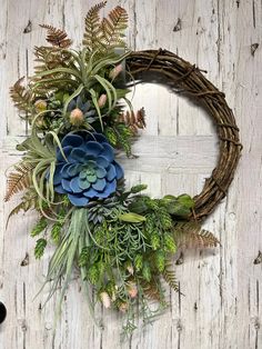 a wreath with blue flowers and greenery hanging on a wall