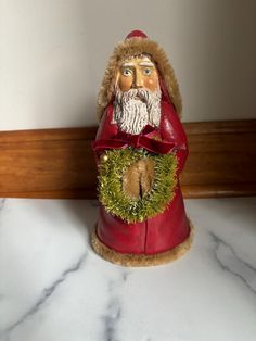 a santa clause figurine with a wreath on it's head sitting on a marble counter