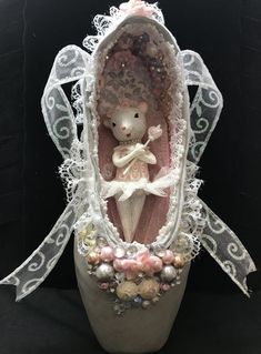 a little mouse in a shoe decorated with pearls and lace on a black background,