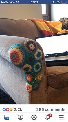 a couch with a laptop on top of it and a crocheted arm rest