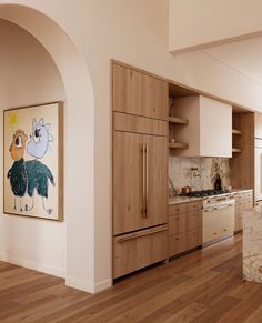 a kitchen with wood floors and white walls has an art piece on the cabinet door