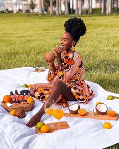 a woman sitting on top of a blanket next to oranges