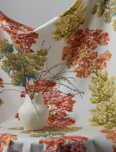 a vase filled with flowers sitting on top of a white table covered in a floral fabric