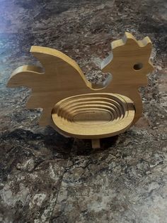 a wooden toy that looks like a chicken on top of a table with marble counter tops