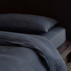 an unmade bed with dark blue sheets and pillows