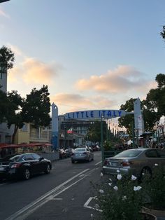 cars are driving down the street in front of some shops and businesses at sunset or dawn