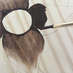 a drawing of a flower being worked on by a person with a paintbrush in their hand