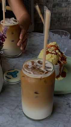 two drinks are sitting on a table next to some plates with desserts and flowers