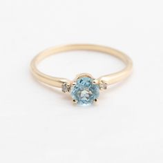 an oval blue topaz ring with three diamonds on the sides and a yellow gold band