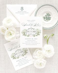 the wedding stationery is displayed with white flowers and greenery