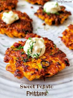 sweet potato fritters on a white plate with sour cream in the middle and fresh herbs sprinkled on top