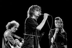 three people on stage singing into microphones