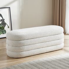 a stack of white towels sitting on top of a wooden floor next to a window