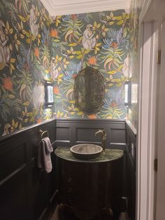 a bathroom with wallpaper and a sink in it's corner next to a mirror