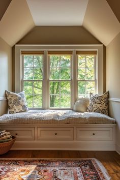 a window seat in the corner of a room with pillows and rugs on it