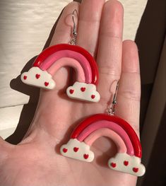 pair of pink and red earrings with hearts in the shape of a rainbow on hand