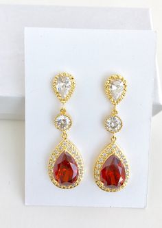 I've created these gorgeous red ruby cubic zirconia bridal tear drop earrings in gold plated brass setting. Earrings feature a large teardrop with pear cut red ruby cubic zirconia center surrounded by tiny round zirconia crystals. Teardrop dangles from a clear cubic zirconia ear stud and a round cubic zirconia connector. Total length of the earring is 4.8 cms. For matching necklace click: https://www.etsy.com/listing/667778454/red-bridal-gold-necklace-red-crystal?ref=related-6 For matching brace Elegant Red Teardrop Bridal Earrings, Red Ruby Pear-shaped Earrings, Red Pear-shaped Wedding Earrings, Red Dangle Bridal Earrings For Anniversary, Red Ruby Earrings For Wedding, Red Ruby Wedding Earrings, Elegant Red Cubic Zirconia Bridal Earrings, Red Teardrop Earrings For Anniversary, Red Pear-shaped Cubic Zirconia Earrings