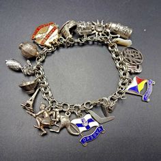 "VINTAGE WORLD TRAVEL CHARM BRACELET DESCRIPTION: This exquisite collectible features an abundance of sterling silver charms, some very interesting and rare additions. BOOMERANG SS ORSOVA FLAG (from the Orient Steam Navigation Company 1954-66 and Peninsular and Oriental Steam Navigation Company 1966-74 KANGAROO ABORIGINAL INDIGENOUS AUSTRALIAN HUNTER EIFFEL TOWER WOK with CHOPSTICKS PINEAPPLE from HAWAII (not sterling) CHINESE KONGMING LANTERN THEATRE MASK (Sock and Buskin Comedy/Tragedy) REDLIN Collectible Symbolic Charm Jewelry, Antique Souvenir Jewelry With Charms, Collectible Silver Vintage Charm, Silver Symbolic Jewelry Souvenir, Collectible Vintage Charm Bracelet Jewelry, Vintage Jewelry With Dangling Charms Souvenir, Vintage Jewelry With Dangling Charms As Souvenir, Vintage Dangling Charms Jewelry Souvenir, Sterling Silver Bracelets With Dangling Charms For Collectors