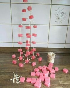 pink marshmallows are arranged on the floor next to a vase and sticks