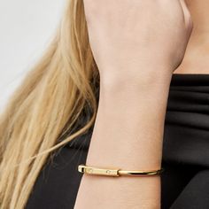 The Tiffany & Co Lock Bangle is all about bringing people together, and this bangle is a bold symbol of those personal connections that shape us. It's made for everyone, no matter your gender, and it has this cool clasp that's like a padlock, inspired by Tiffany's history. The bangle is crafted in 18k yellow gold and has sparkly diamonds for a touch of contrast. With a total carat weight of 0.31 and a medium size fitting wrists up to 6.25 inches, this Tiffany Lock Bangle is a simple, stylish way Tiffany Bangle Tiffany & Co., Tiffany Lock Bangle, Tiffany Lock Bracelet, Dark Books, People Together, Gold Hands, Watch Necklace, Ring Bracelet, Tiffany & Co.