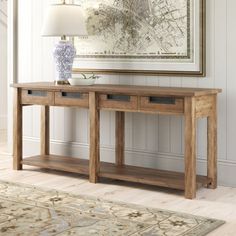 a wooden table with two drawers and a lamp on it in front of a painting