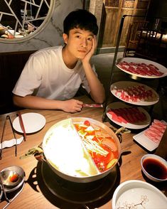 a young man sitting at a table with food on it