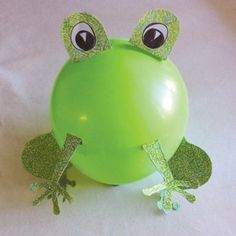 a green frog balloon sitting on top of a white sheet